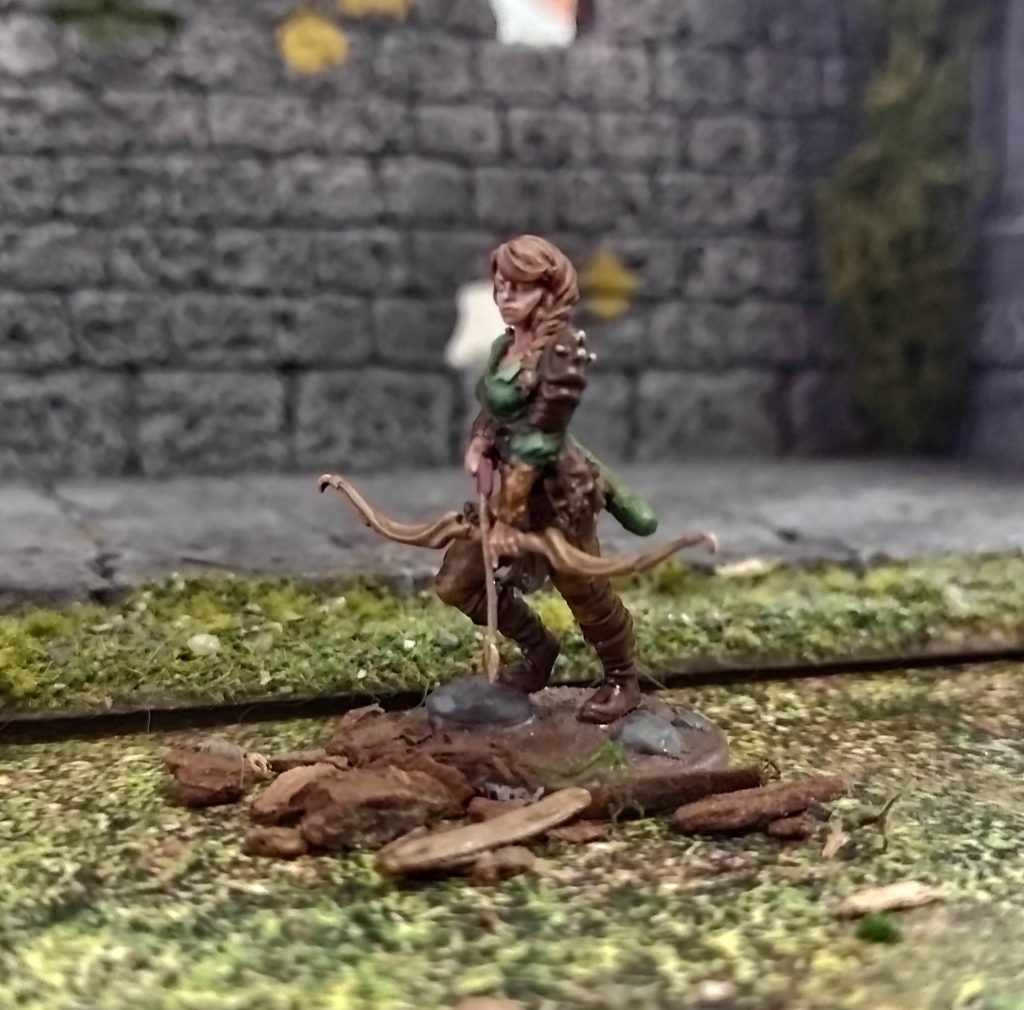 female elf miniature in front of a tabletop scenery wall